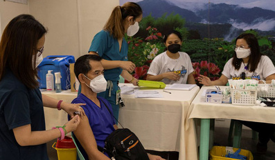 A hospital worker is inoculated with a booster dose